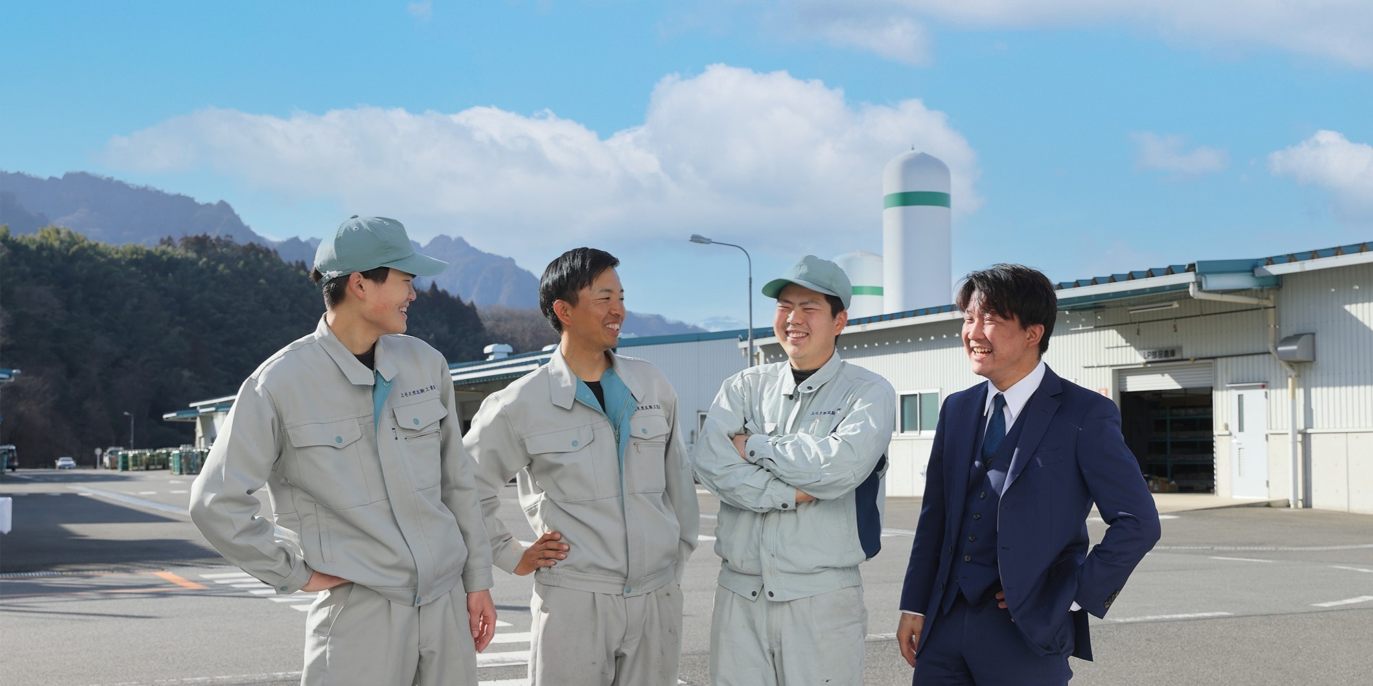 写真：社員５人が青空の元事務所の前で並んでいる